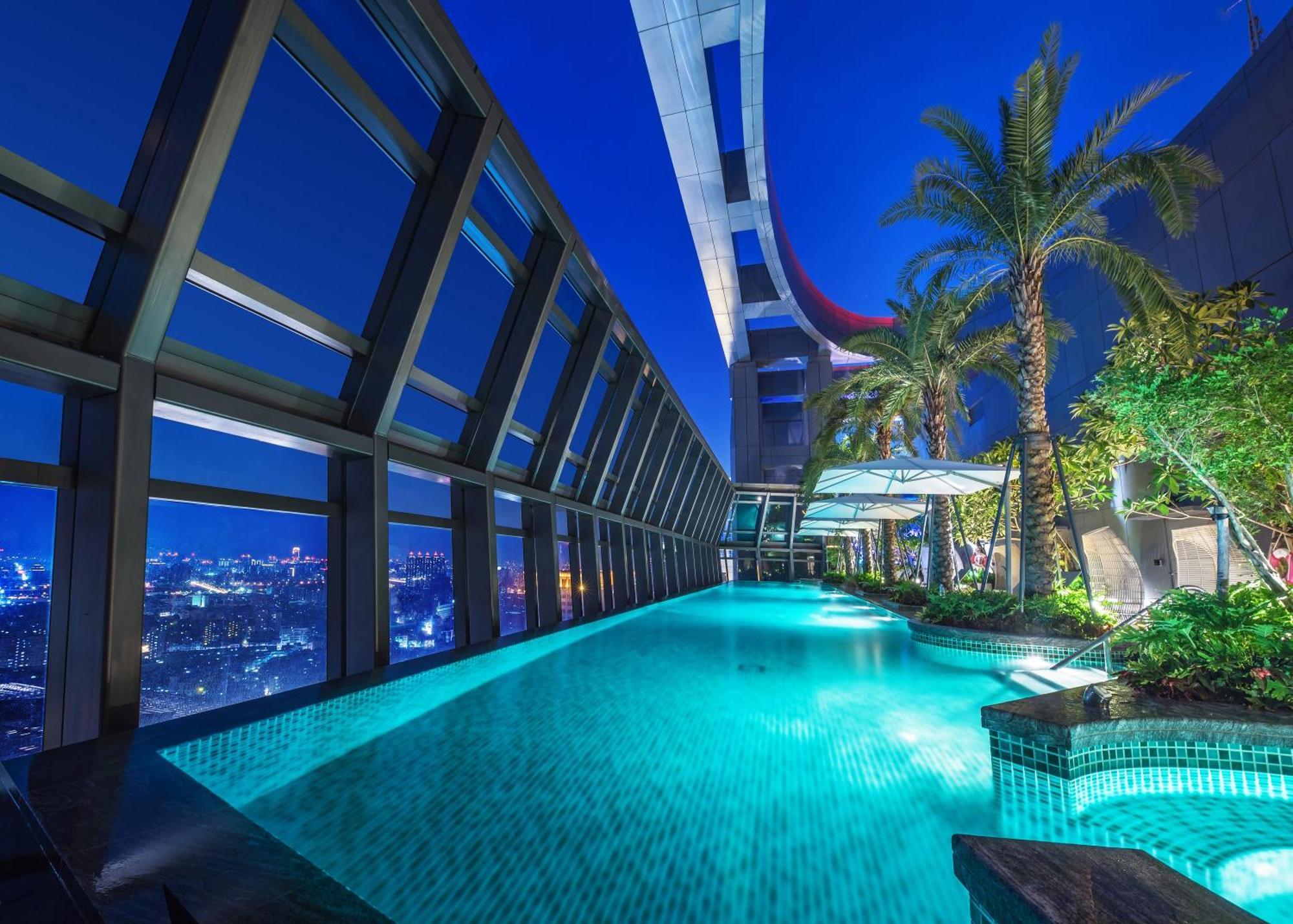 Caesar Park Hotel Banqiao Taipei Exterior photo The photo depicts a luxurious swimming pool situated in a high-rise building, showcasing a stunning view of the city beneath. The pool is illuminated by soft lighting, giving it a tranquil ambiance. Surrounding the pool are modern architectural eleme