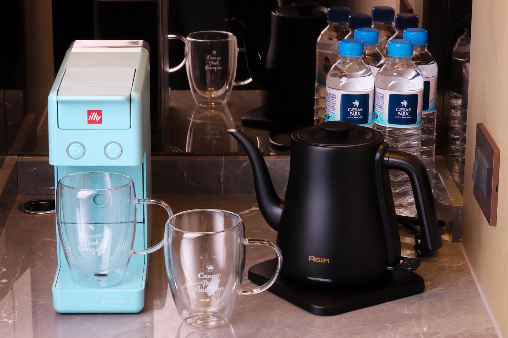 Caesar Park Hotel Banqiao Taipei Exterior photo The photo shows a countertop scene with a couple of kitchen appliances and some drinkware. On the left, there is a light blue coffee machine, likely designed for making espresso or coffee. Next to it, there are two clear glass mugs placed upright. On